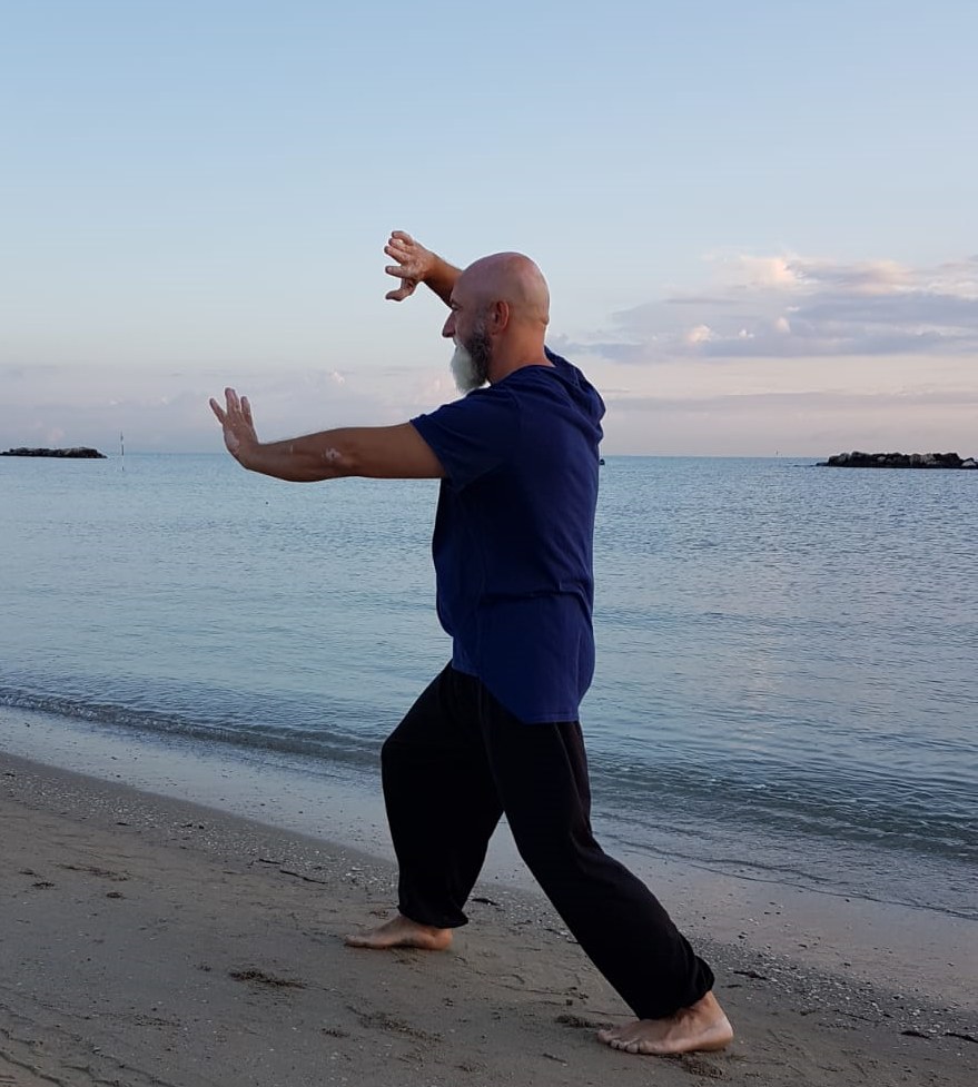 Massimiliano Caporali esegue una posizione di Tai Chi in riva al mare